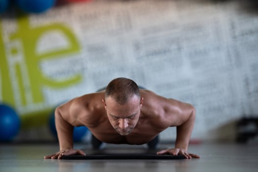A muscular man performing push ups in the gym, showcasing strength, endurance, and dedication to his fitness routine. photo