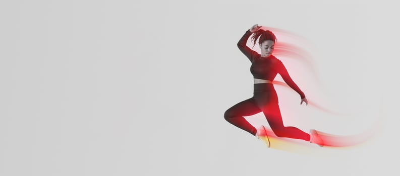 Fitness lifestyle. Motivated African American lady jumping in air over peach neon studio background, athletic woman making jump exercises, enjoying cardio workout, full length, copy space photo