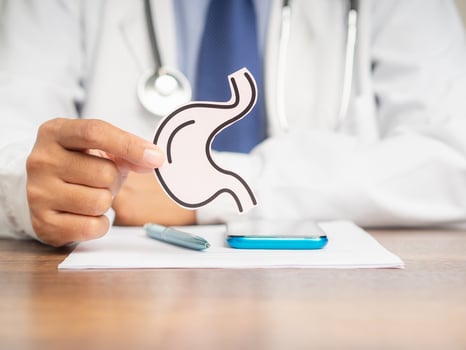 Doctor holding a stomach shape symbol while sitting at the desk photo