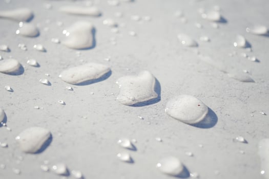 Water drops reflect light on a smooth surface under daylight photo