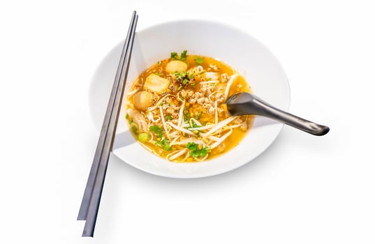 Top view of Spicy TOM YAM pork noodle soup with lemongrass chilly pasted and lime juice, focus selective photo