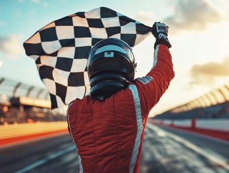 Winning racer celebrates at sunset with checkered flag raised photo
