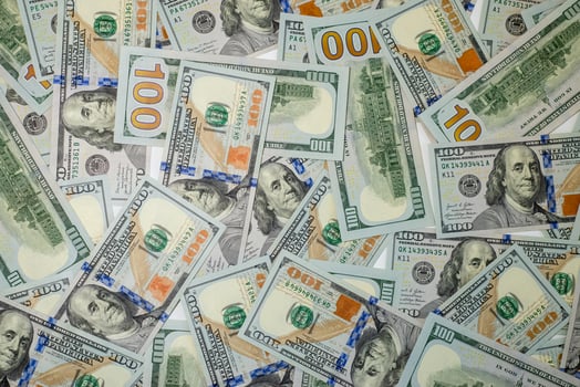Stacks of hundred-dollar bills are spread out on a surface, details of the new currency design photo