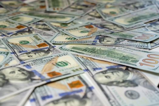 Stacks of hundred-dollar bills are spread out on a surface emphasizing the details of the new currency design side view in close up photo