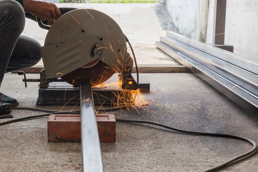 Metal worker cutting metal tube by electric grinding machine. photo