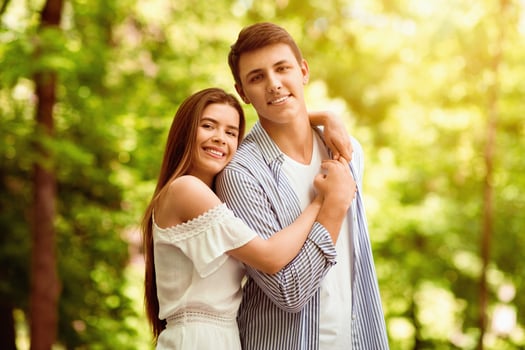 Affectionate girl hugging her boyfriend at beautiful park in summertime photo