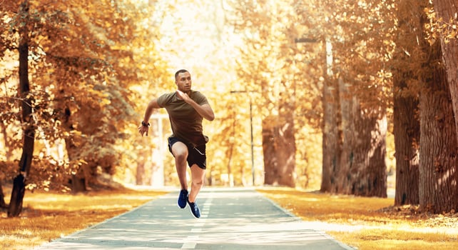 Black sprinter training for race on jogging track at beautiful autumn park, copy space. Panorama photo