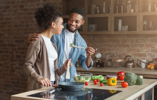Happy african-american couple tasting dinner in loft kitchen at home photo
