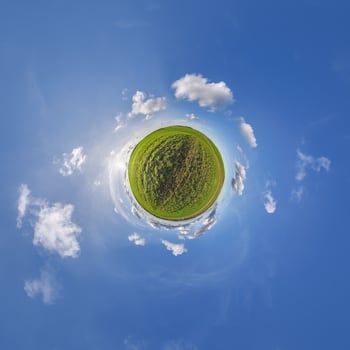 A small planet with a grassy field and clouds photo