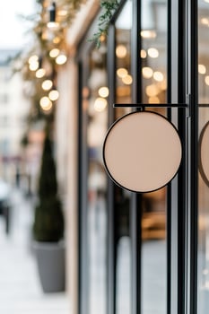 A modern round metal signboard is suspended from a sleek black bracket, enhancing the boutique's aesthetic on a high-end shopping street. Soft reflections dance in the glass windows photo