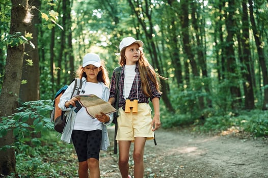 Using ,the map. Two girls is in the forest having a leisure activity, discovering new places photo