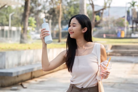Sustainable lifestyle. Young woman appreciating her reusable cup in a park. photo