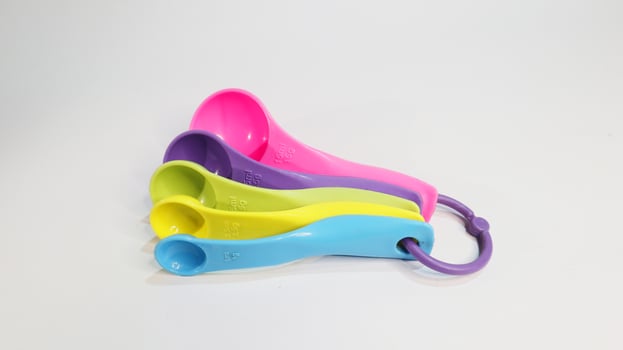 Plastic colored measuring spoons on a white photo