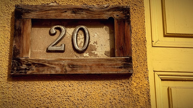 Charming house number on a textured wall in sunlight photo