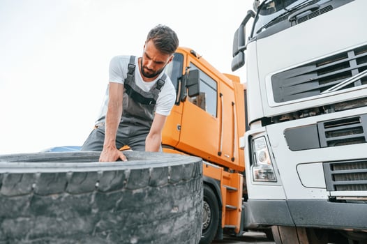 Moving broken tire. Man ,in unifrom doing service for big truck vehicle photo