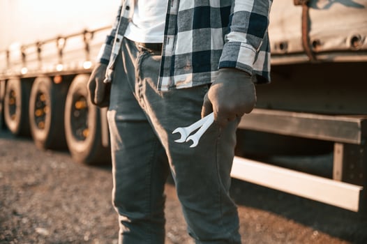 Close up view. Holding, wrenches. Young truck driver is with his vehicle at daytime photo