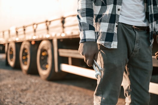 Close up view. .Holding wrenches. Young truck driver is with his vehicle at daytime photo
