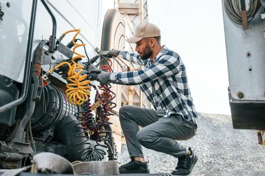 Checking, the wires connection. Young truck driver is with his vehicle at daytime photo