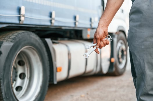 Holding wrench. Man in unifrom doing service for big truck vehicle photo