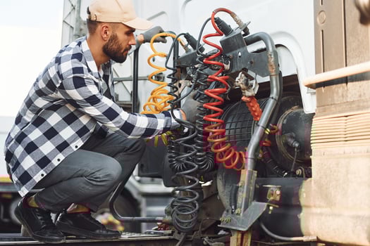 Fixing wires connection. Young truck driver is with his vehicle at daytime photo