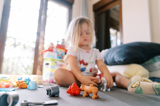 Little girl plays with Lego toys while sitting on the bed photo