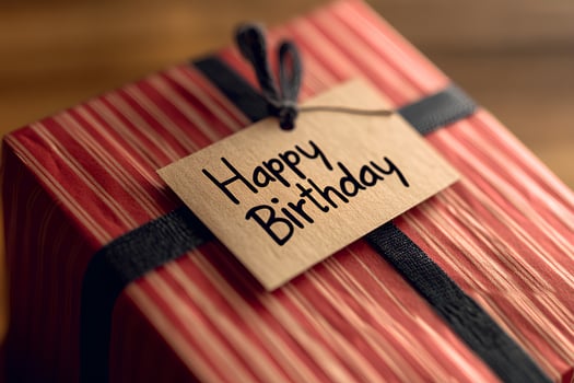 Close up of a beautifully wrapped gift box with a Happy Birthday card on a rustic wooden background photo