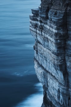 A cliff face with a blue sky and ocean photo