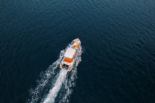 Motor yacht sails on the sea leaving a white foamy trail. Drone photo