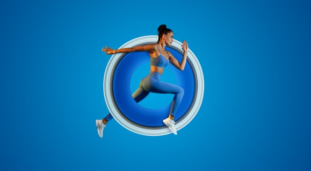 Side View Of Determined Young Sportswoman Jumping Posing In Mid-Air Looking Aside On Blue Studio Background. Serious Fitness Lady Running In Air. Panorama, Full Length photo