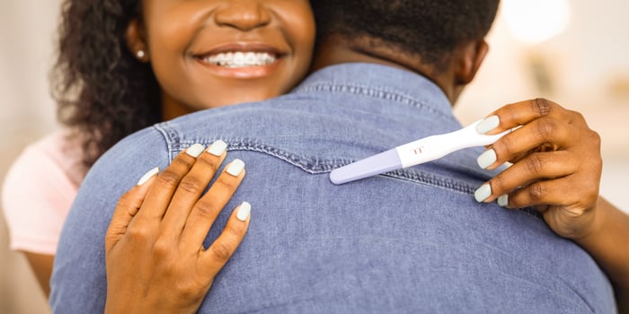 Cropped of happy african american woman with positive pregnancy test hugging her husband photo