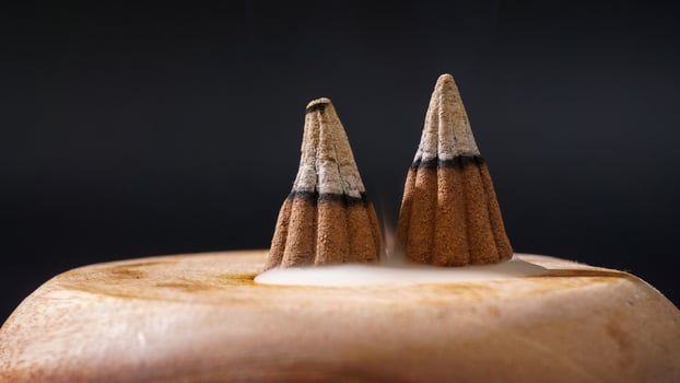 Burned incense cones for aromatherapy on wooden base isolated on black background photo