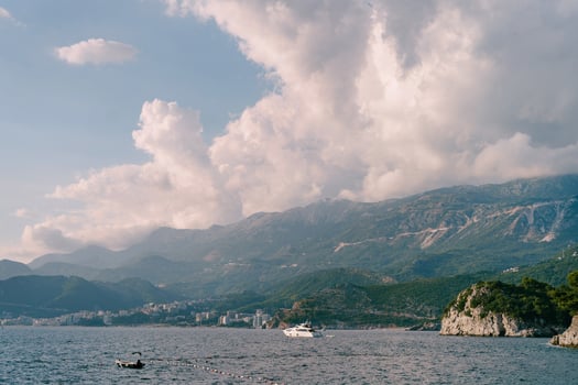 Motor yacht sails on the sea along the mountain coast photo