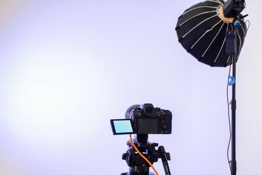 Back view camera on tripod and studio lights with blank screen backdrop photo