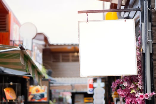 Blank vintage sign board hanging on pole at small old restaurant in the market. photo
