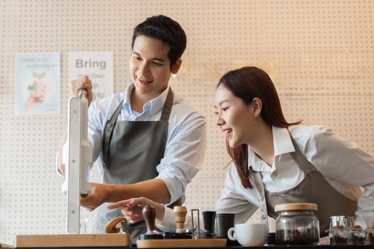 Training in Coffee Mastery. A barista demonstrating brewing techniques engaging a learner in a cafe environment. photo