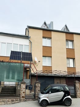 Lviv, Ukraine - March 12, 2025 - Urban residential building with solar panels and parked compact Smart Fortwo car photo