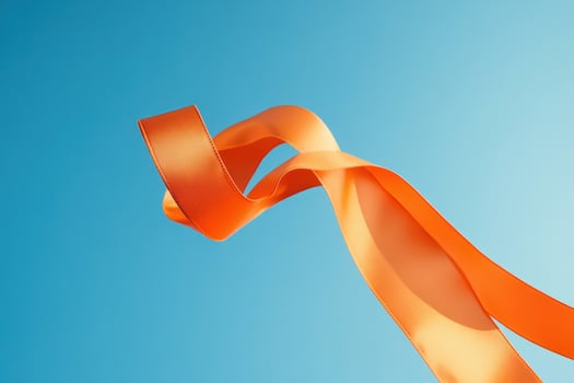 Orange ribbon flowing against a blue sky photo