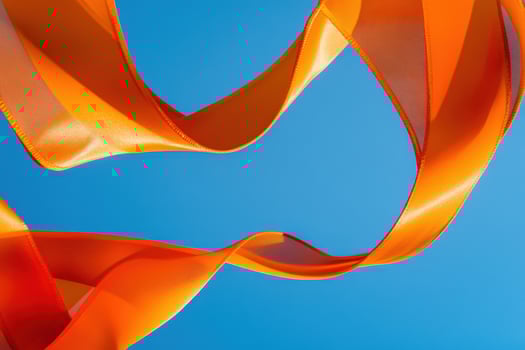 Orange Fabric Ribbon Waves Against Blue Sky photo