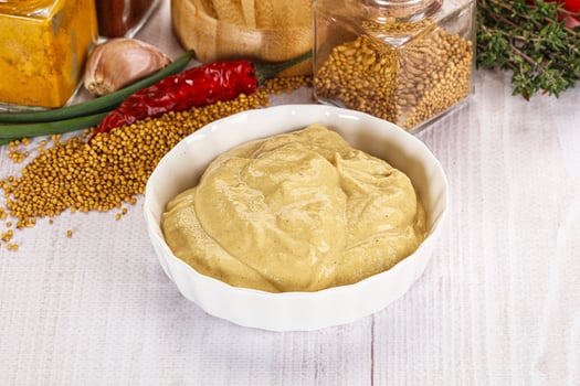A bowl of mustard next to a bowl of spices photo
