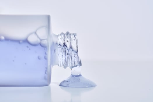 A cosmetic bottle from which a blue emulsion is poured. photo
