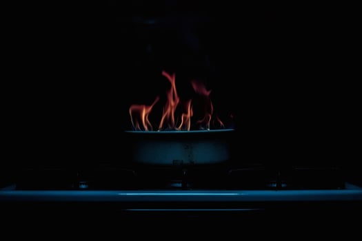 Fire dances on the stove in a dark kitchen. photo