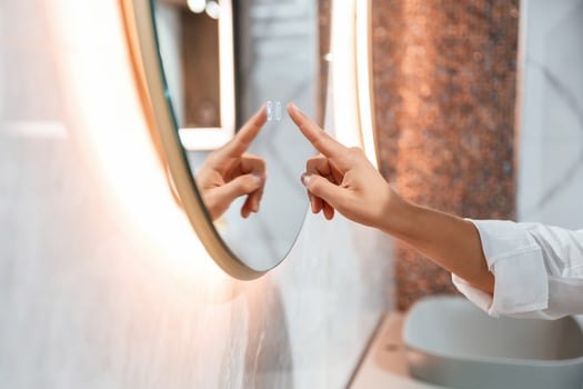 Using, the mirror with touchscreen feature. Pretty young woman is in the store of goods for the home photo