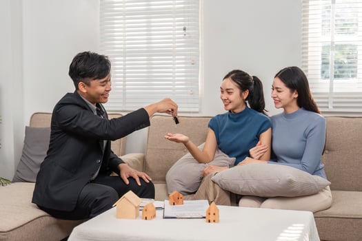 Property Keys Exchange. A real estate agent hands over keys to two excited clients during a property deal. photo