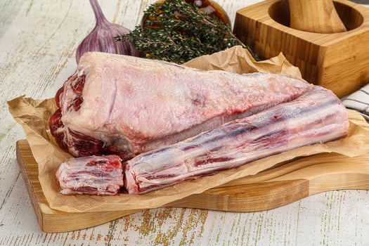 A raw lamb leg on a wooden cutting board photo