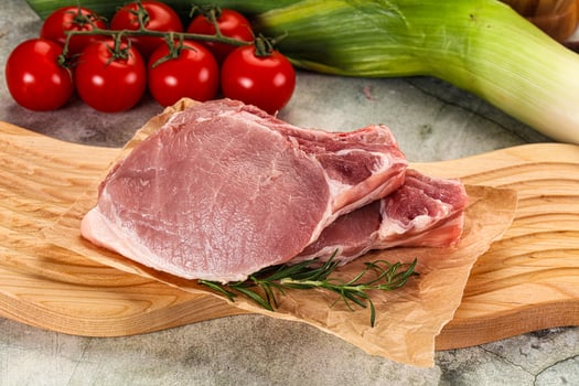 Raw pork on a cutting board with vegetables photo