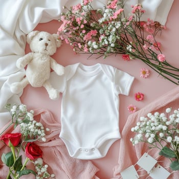 A teddy bear, flowers and a baby onesie on a pink background photo