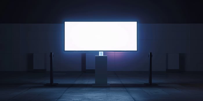 An empty billboard stands in a dark room photo
