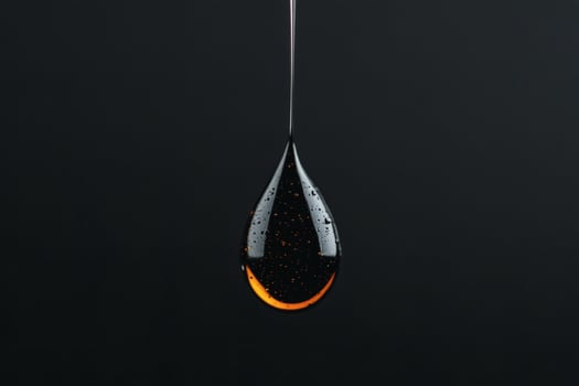 Captivating drop of dark liquid illuminated in the dark. photo