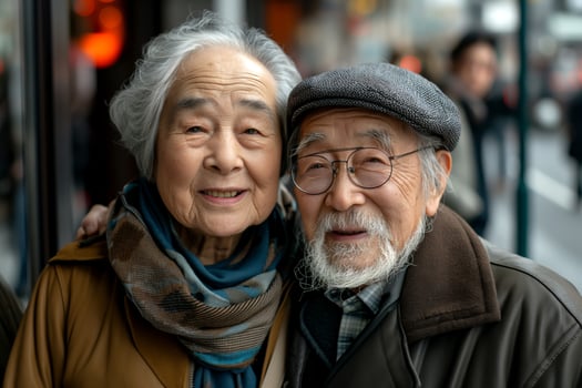 A joyful elderly couple, an Asian woman and man, share a warm embrace outdoors, radiating love and longevity in their smiles. photo