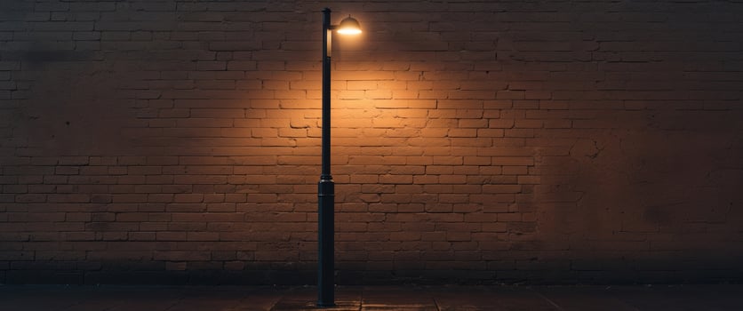 Cozy evening street scene with lit lamp post and brick wall photo